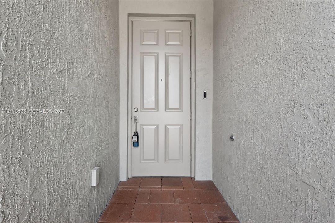 Entryway featuring a six-panel door, neutral stucco exterior walls, and tiled flooring