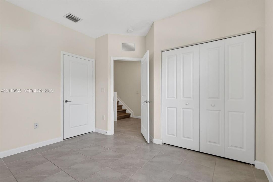 Neutral-toned interior featuring large-format ceramic floor tiling, white panel interior doors