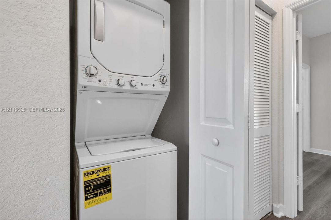 Stackable laundry unit featuring a white finish and louvered bi-fold closet doors