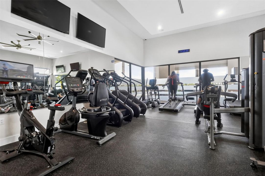 Fitness facility featuring high ceilings, wall-to-wall mirrors, recessed lighting, rubberized flooring, and expansive floor-to-ceiling glass paneling
