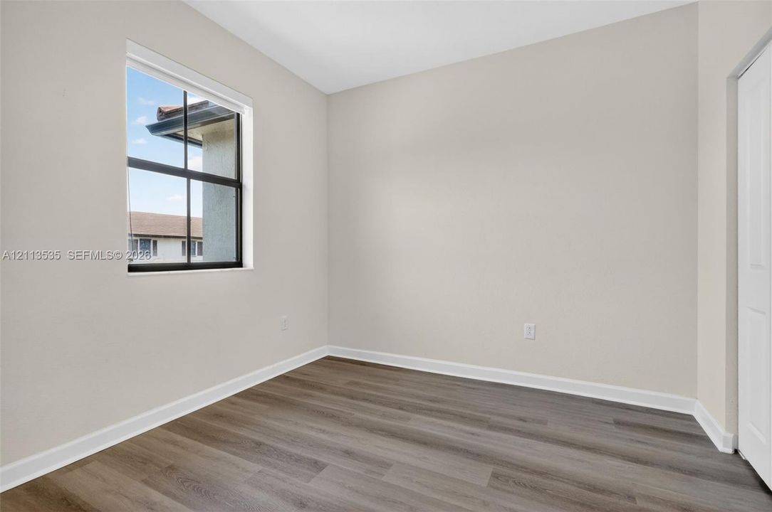 Neutral wall finishes, wood-finish flooring, and a single-hung window featuring a black frame and muntins