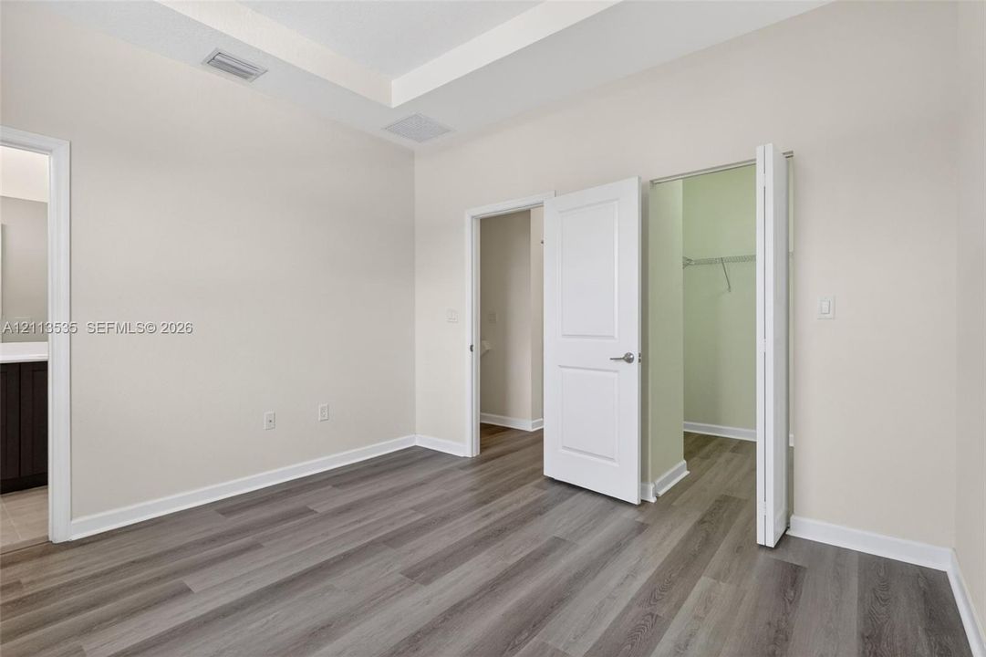 Tray ceiling, wood-finish flooring, and white interior doors featuring satin nickel hardware