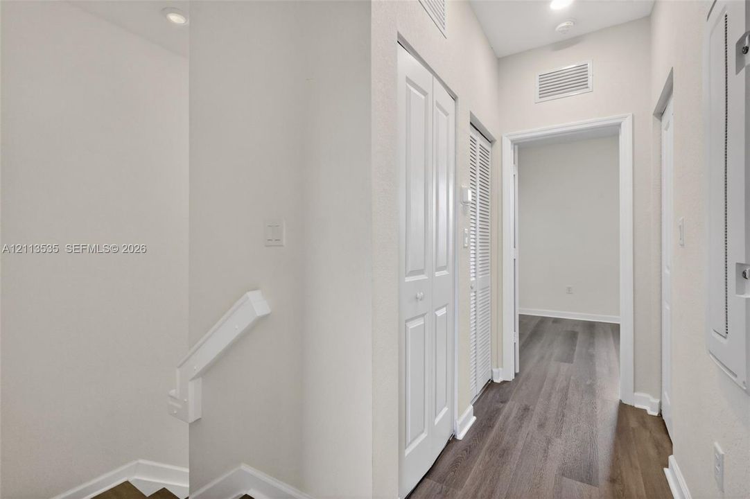 Hallway featuring wood-finish flooring, recessed lighting, and multiple interior paneled doors