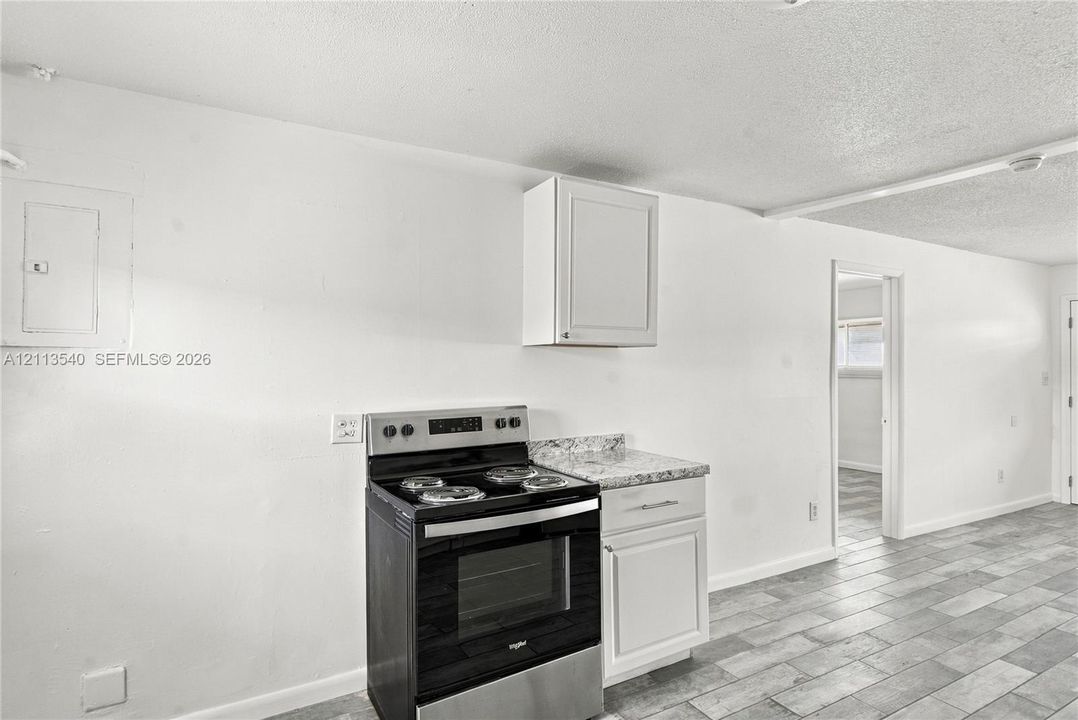 Kitchen featuring white cabinetry, stone-finish countertops, stainless steel electric range, and ceramic tile flooring