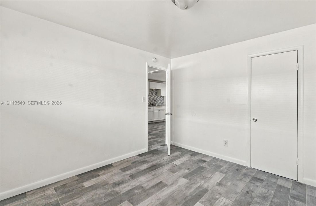 Interior space featuring neutral wall tones, wood-finish flooring, and a flush-mount ceiling light fixture