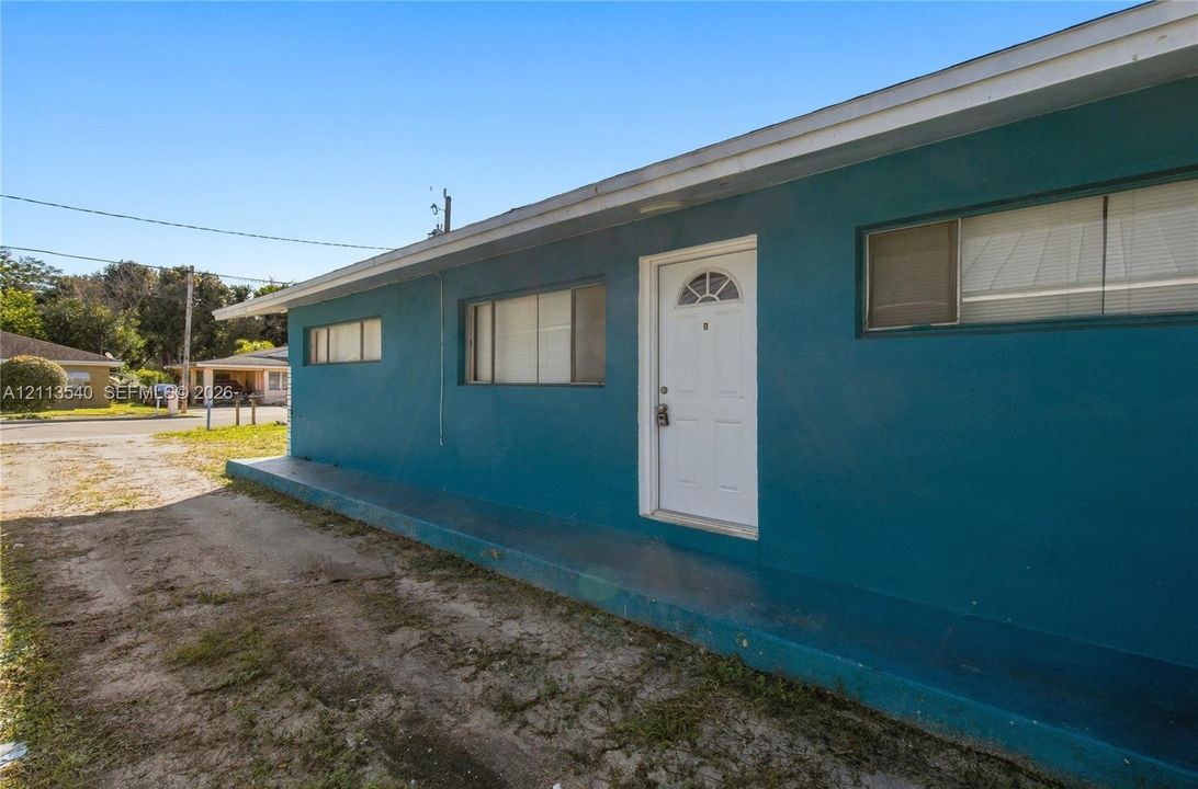 Exterior featuring a smooth-finish teal facade, concrete porch, and horizontal sliding windows