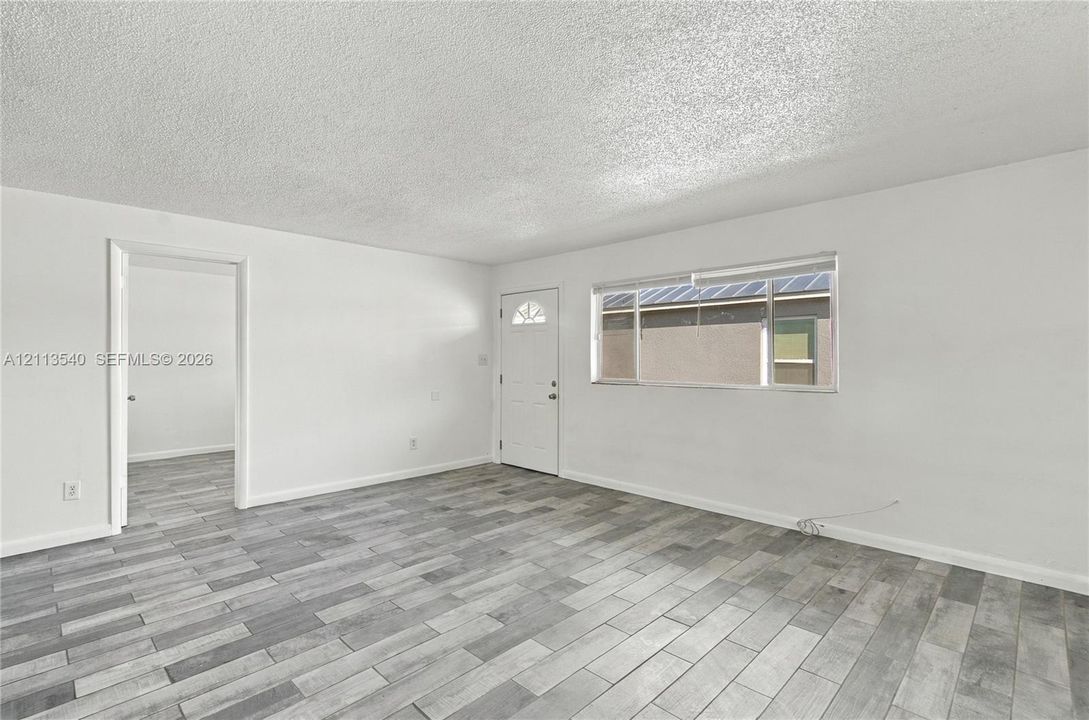 Interior space featuring wood-finish flooring, white walls, a textured ceiling, and a single-light entry door
