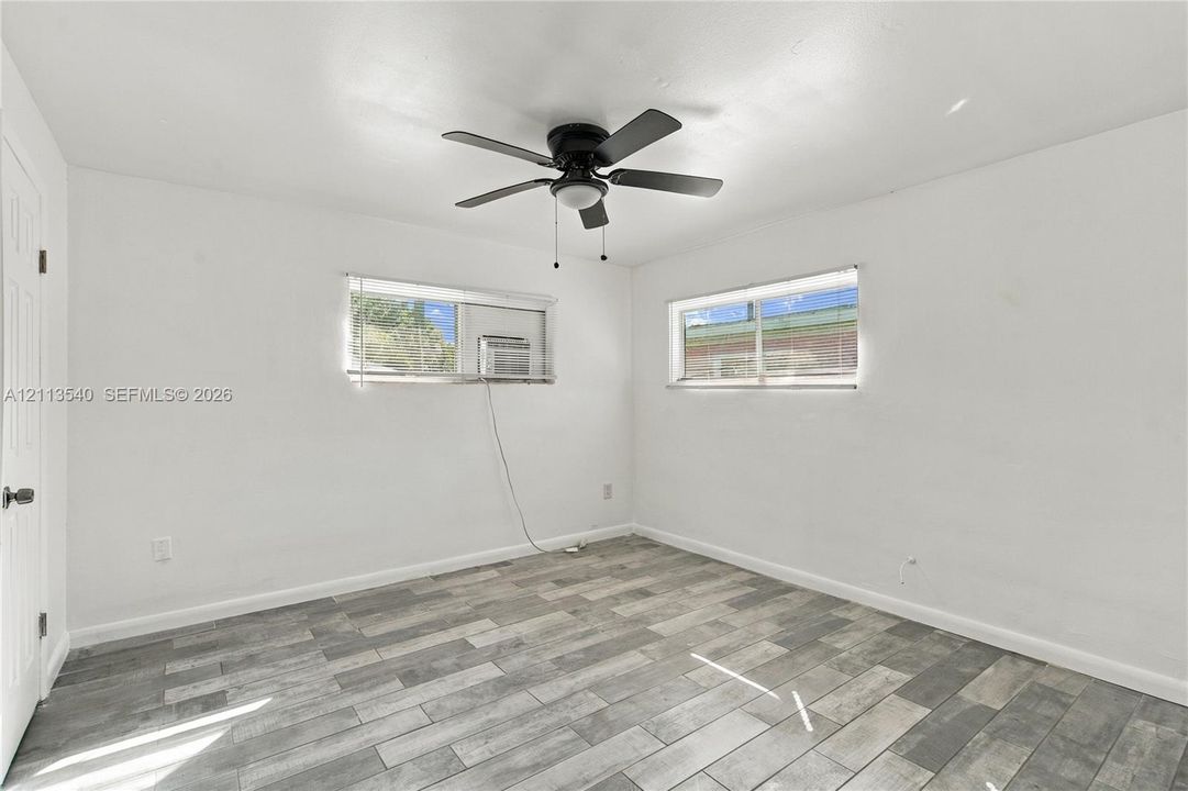 Room featuring neutral walls, wood-finish flooring, and a ceiling fan with integrated lighting