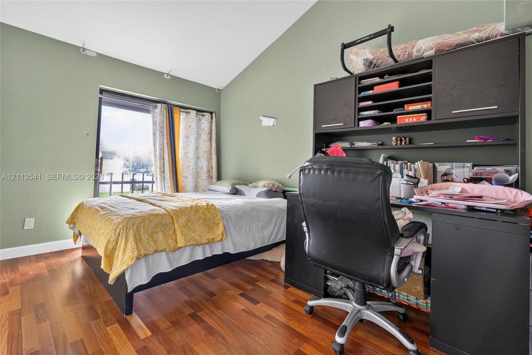 Vaulted ceiling, wood-finish flooring, and natural light from the sliding glass door