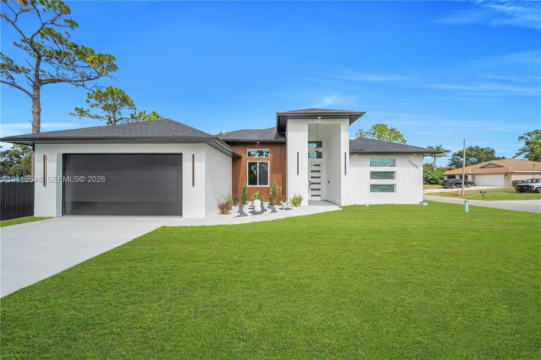 Contemporary exterior featuring smooth stucco finish, vertical wood-paneling accents, horizontal glass-paneled entry door, clean-lined rooflines, and a paved concrete driveway