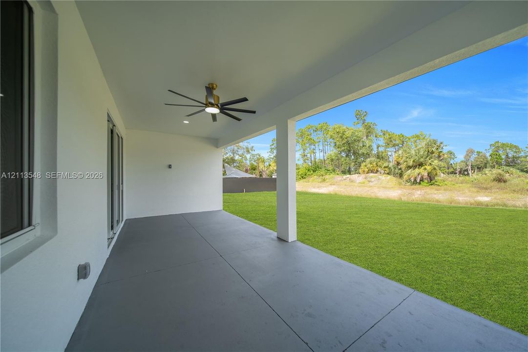 Covered patio featuring a concrete floor, recessed lighting, and a multi-blade ceiling fan overlooking a spacious grass lawn