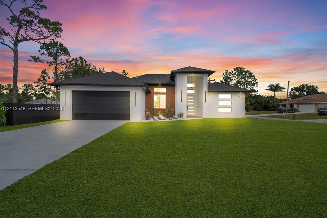 Contemporary exterior featuring smooth stucco finish, vertical wood-panel accenting, multi-level roofline, integrated wall lighting, and a concrete driveway