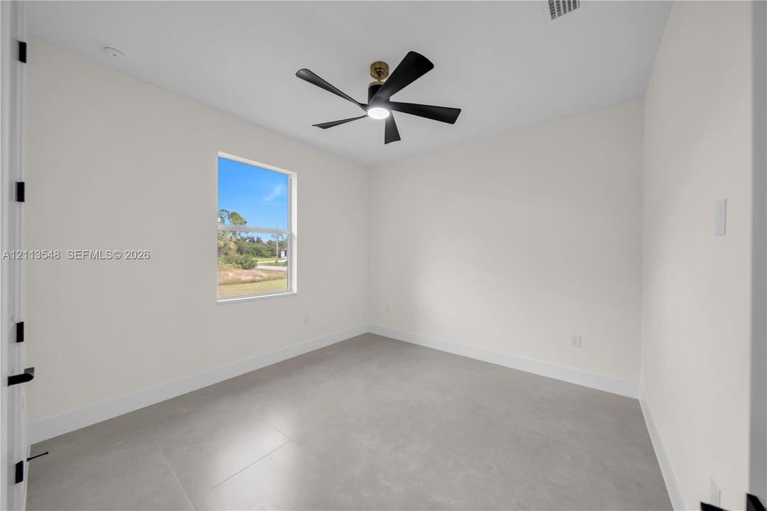 Interior room featuring large-format tile flooring, neutral walls, and a modern ceiling fan with integrated lighting
