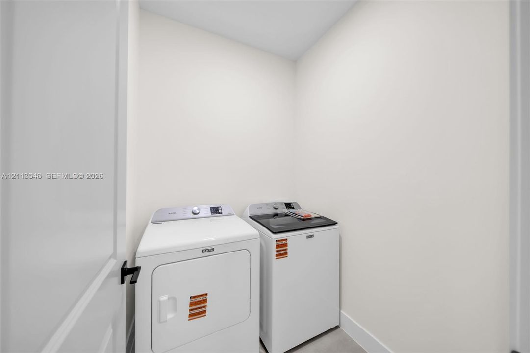 Dedicated laundry room featuring solid-surface flooring, neutral wall finishes, and a matte black door handle
