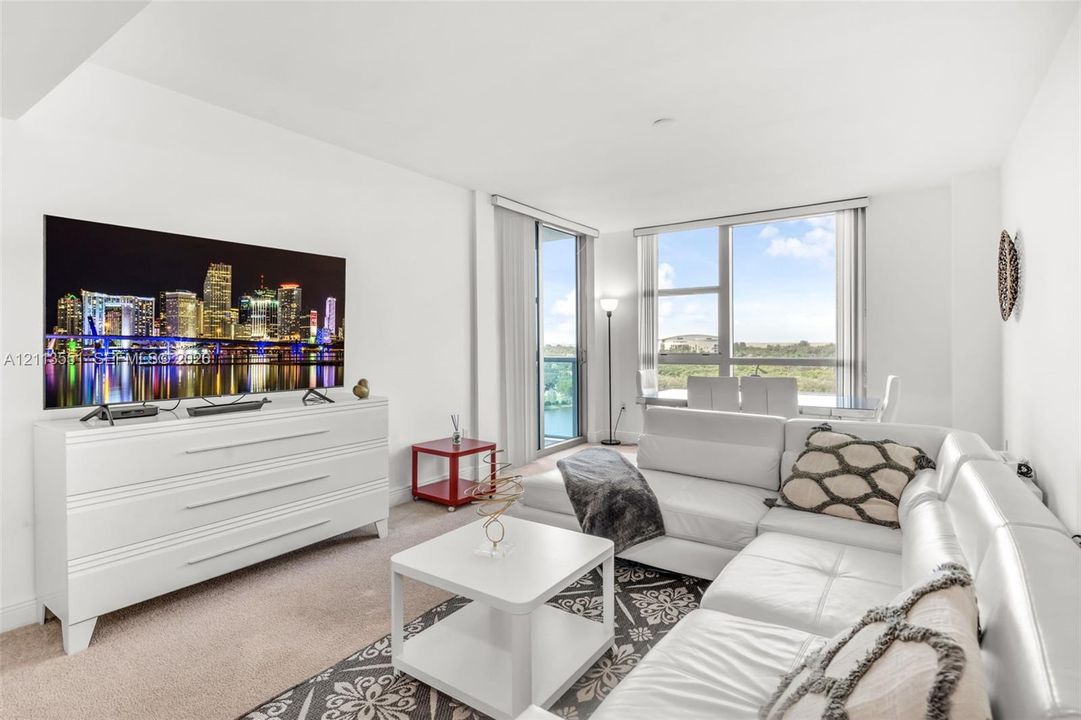 Living area featuring wall-to-wall carpeting, expansive floor-to-ceiling windows, and a sliding glass door providing external access