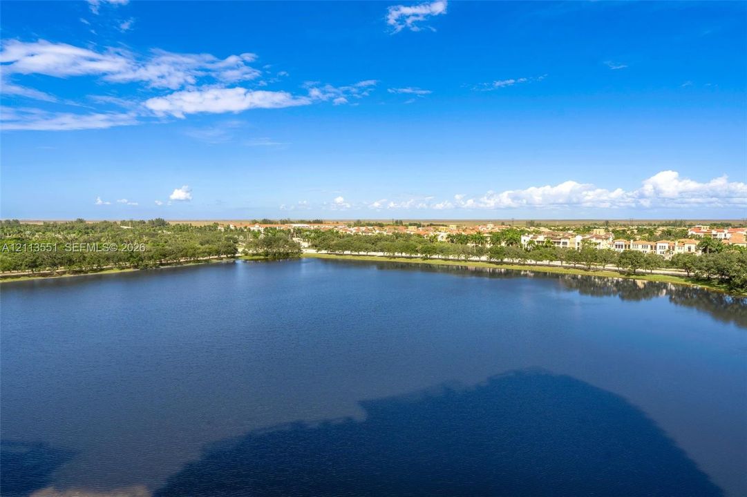 Aerial perspective of a large, open-water lake bordered by mature trees and residential development