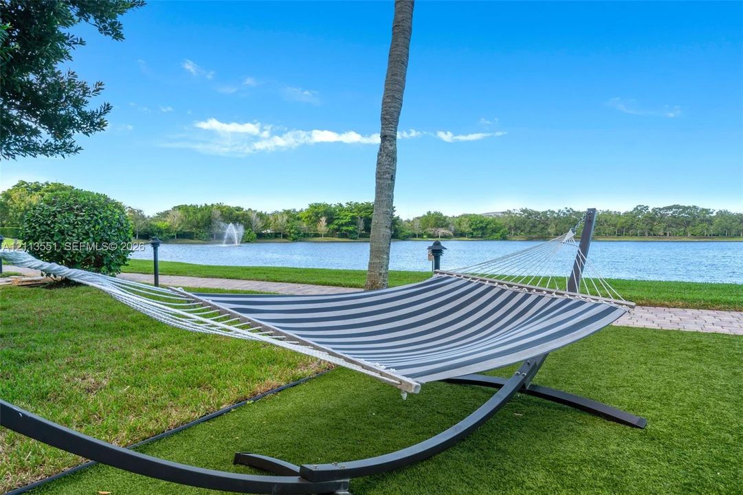 Waterfront lawn featuring a stone-paver path, mature palm tree, and decorative water fountain