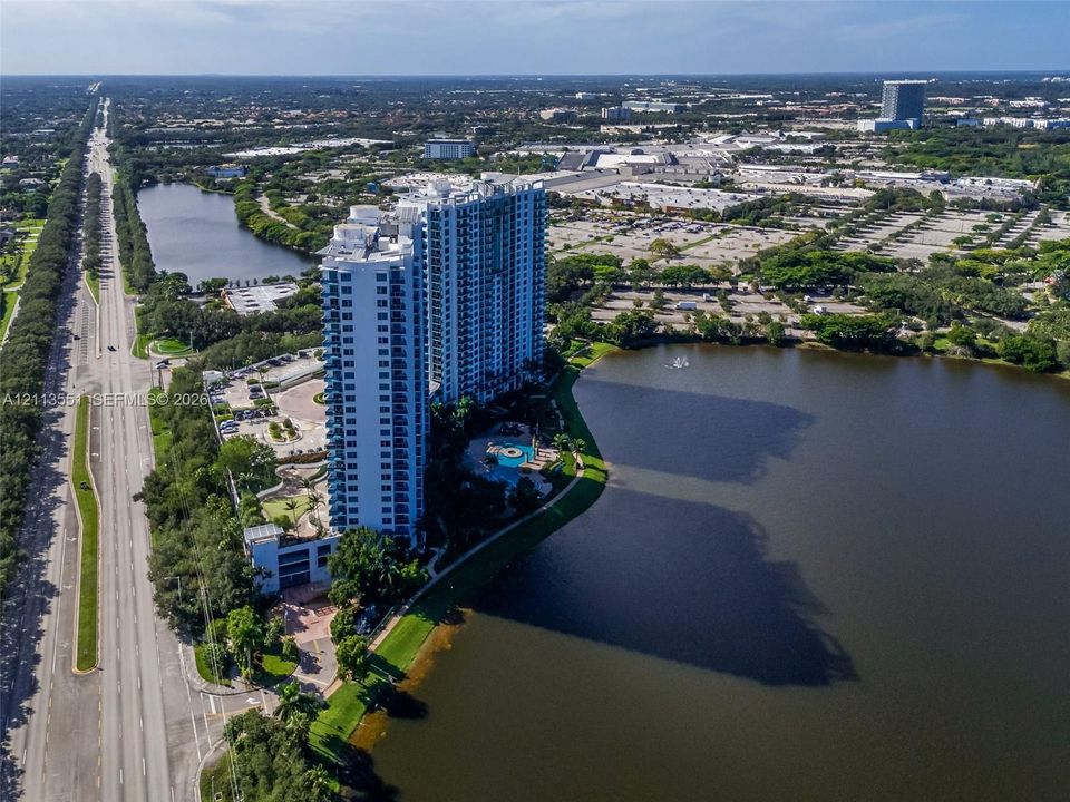 High-rise residential tower featuring a swimming pool, integrated parking structure, and extensive lakefront property boundaries