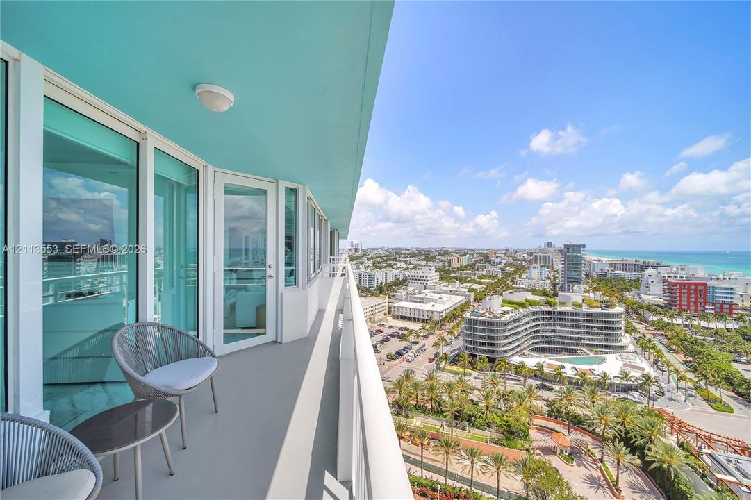 Wrap-around balcony featuring glass railing, neutral-toned flooring, and expansive exterior access through floor-to-ceiling glass paneled doors