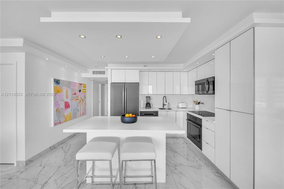 Kitchen featuring flat-panel white cabinetry, a center island with a stone countertop, recessed lighting, and stone-finish flooring