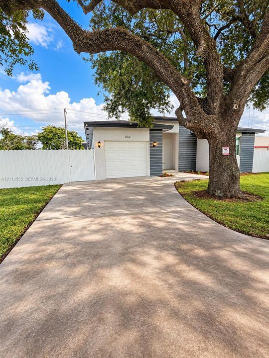 Exterior facade featuring horizontal siding and a single-car garage, concrete driveway, and white privacy fencing