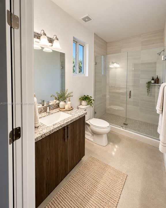 Bathroom featuring a dark wood-finish vanity with a stone countertop, an integrated rectangular sink, a glass-enclosed walk-in shower with tile surround, and a three-light wall-mounted vanity fixture