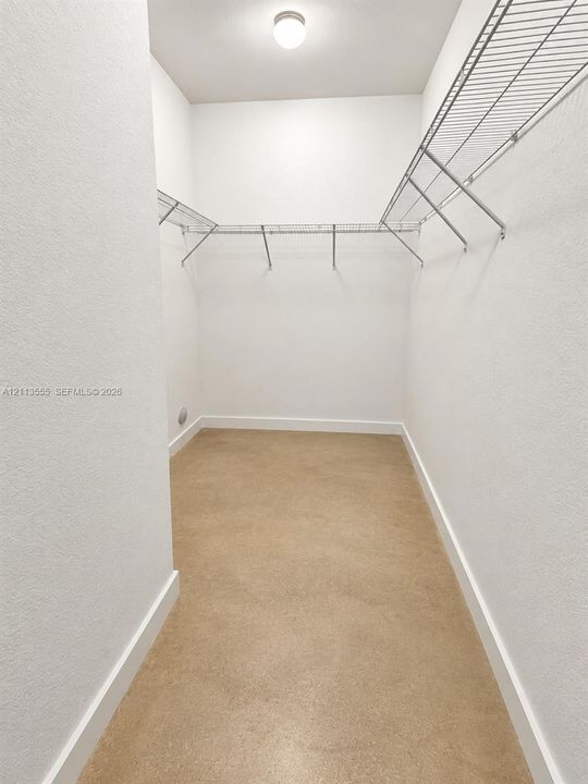 Walk-in closet featuring neutral walls, wire shelving, a ceiling-mounted light fixture, and solid-surface flooring