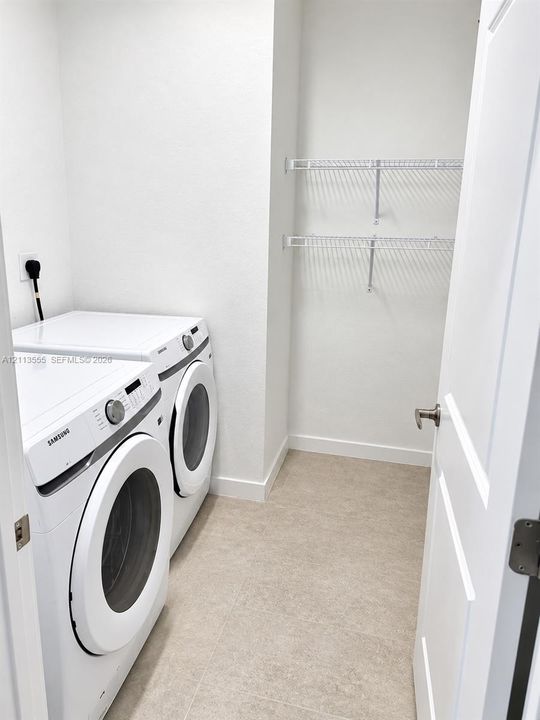 Laundry room featuring tile flooring, white interior walls, and dual-tier wire shelving