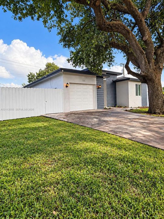 Single-story exterior featuring a stucco and horizontal siding facade, an attached garage, a concrete driveway, and a fenced perimeter