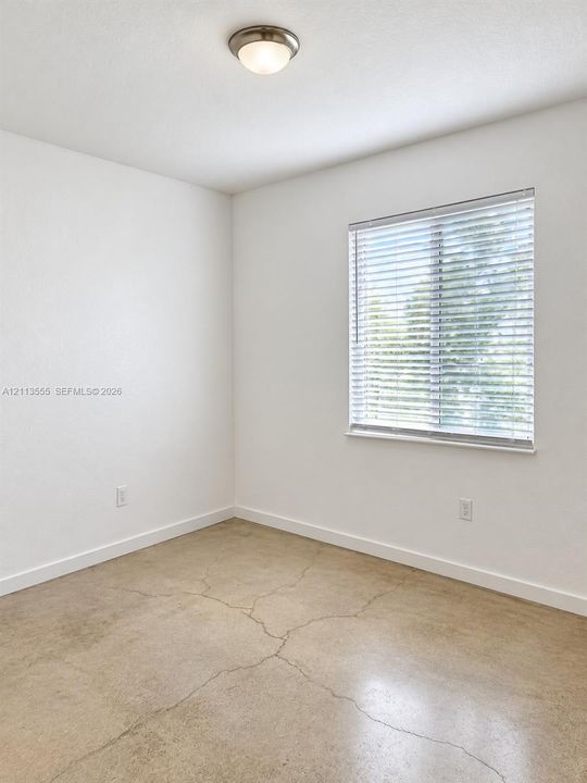 Polished concrete flooring, neutral wall finish, horizontal window blinds, and a semi-flush mount ceiling fixture
