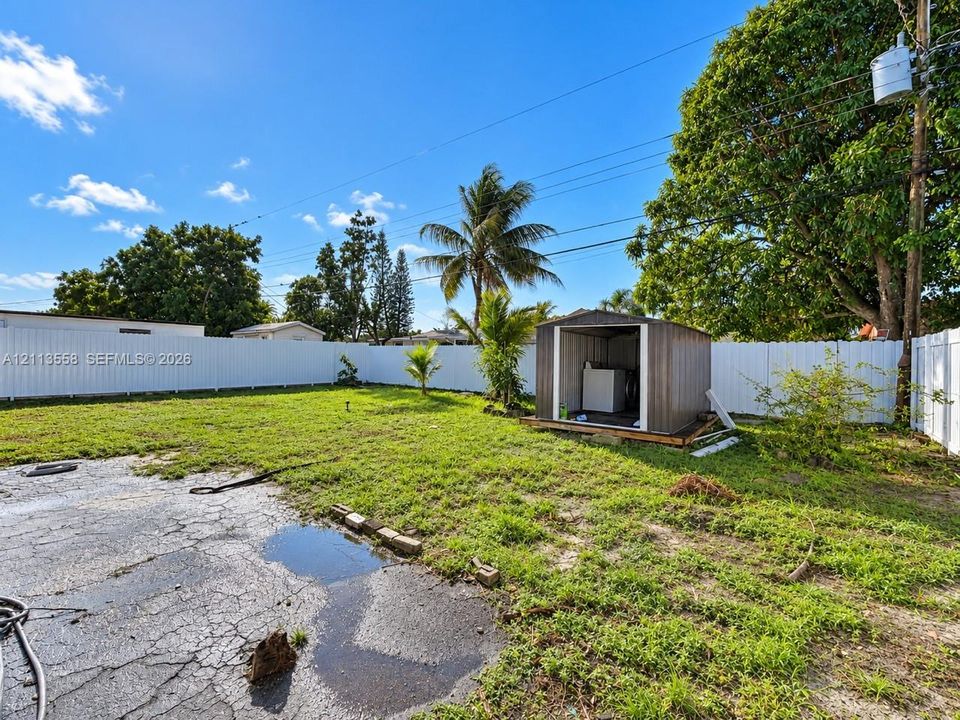Fenced backyard featuring an expansive lawn and a metal storage shed