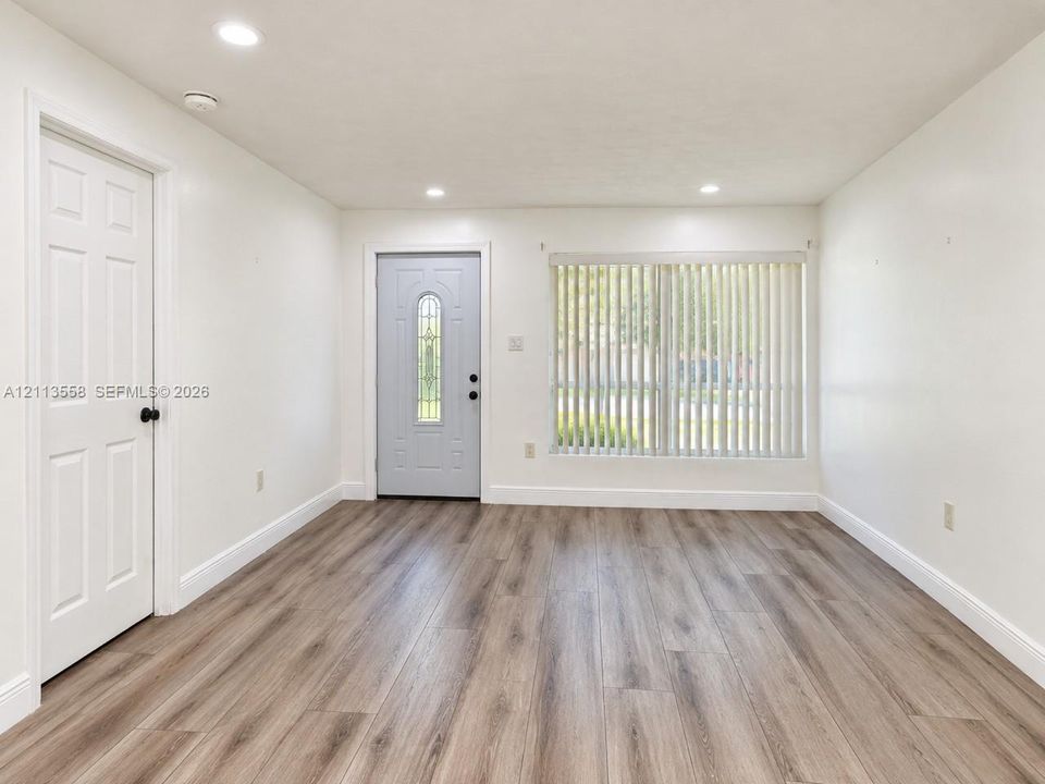 Neutral-toned wood-finish flooring, recessed lighting, and a six-panel door with an arched glass insert