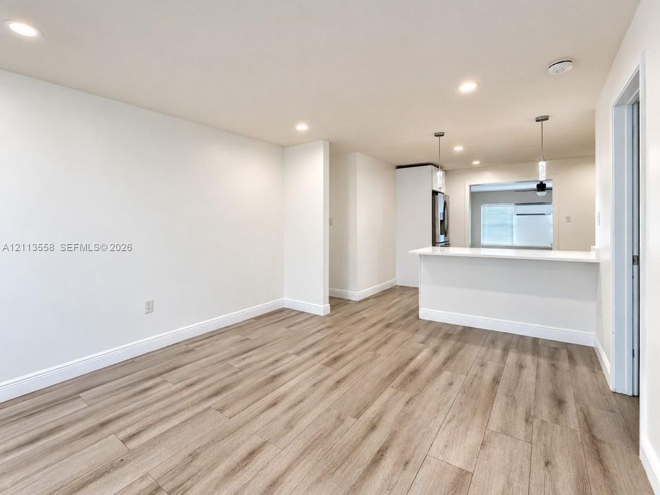 Wood-finish flooring throughout with recessed lighting, breakfast bar, and pendant lighting