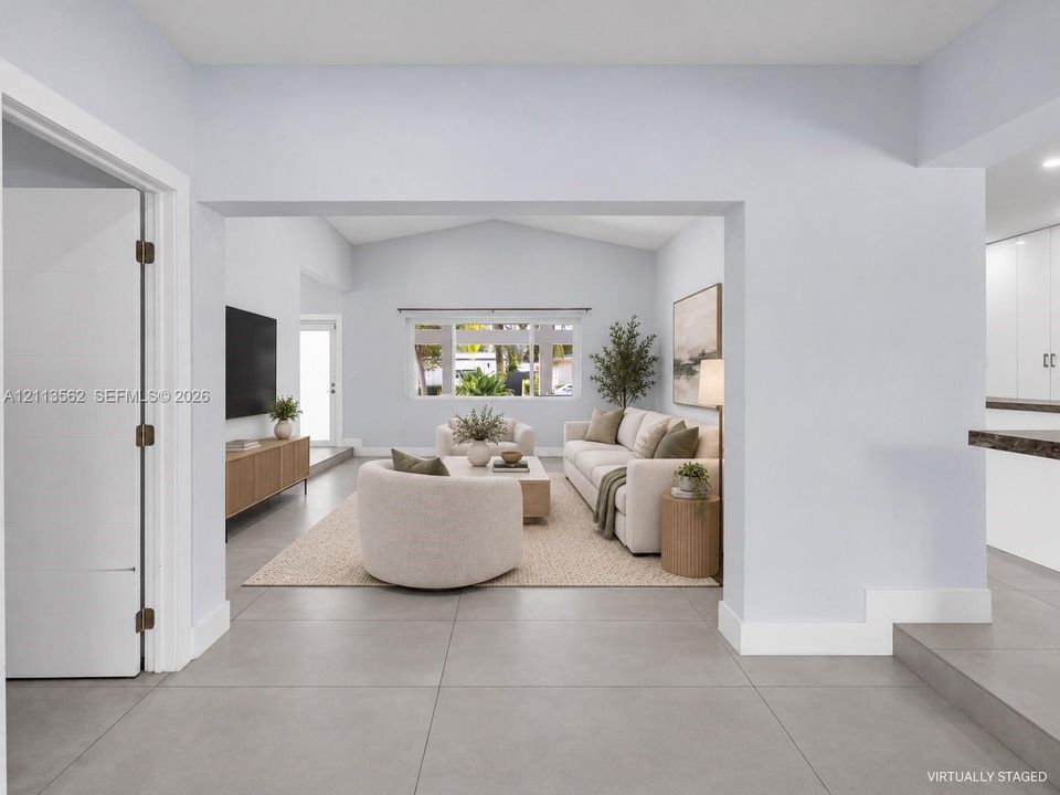 Large-format tile flooring, vaulted ceilings, and natural light from a multi-panel window