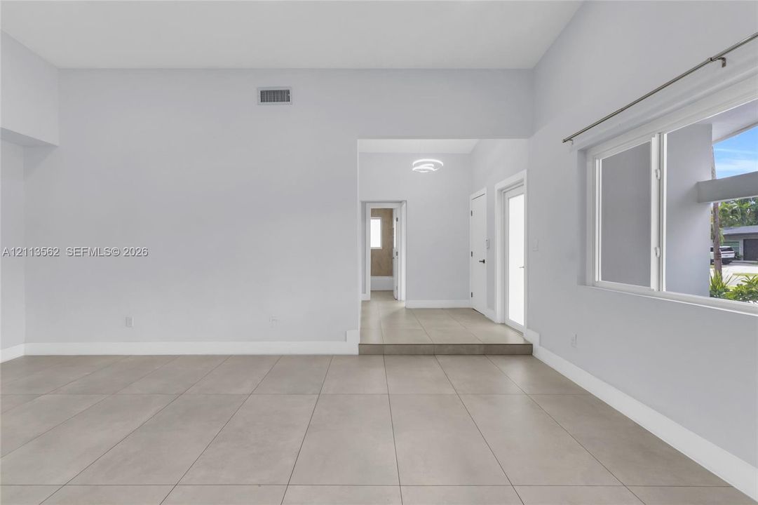 Open-concept interior featuring large-format ceramic tile flooring, vaulted ceilings, and horizontal sliding windows
