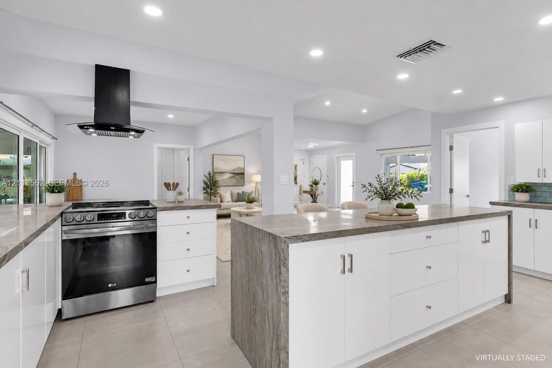 Kitchen featuring white cabinetry, stone-surface countertops, center island, stainless steel slide-in range, and a wall-mounted range hood