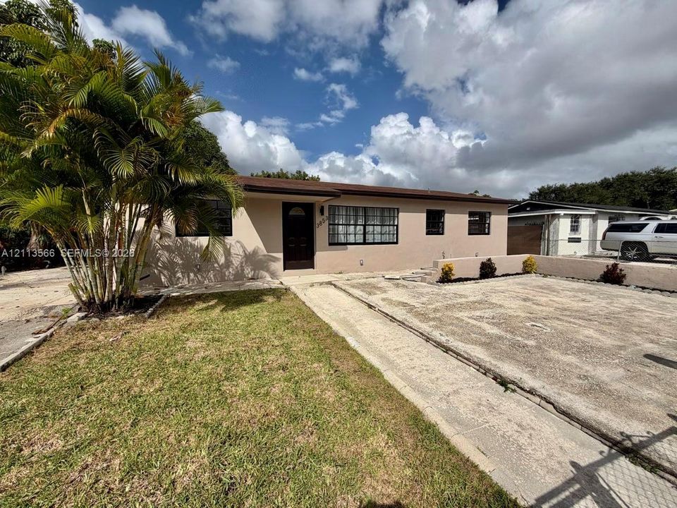 Single-story stucco exterior featuring a flat roofline, grid-patterned windows, and a concrete driveway