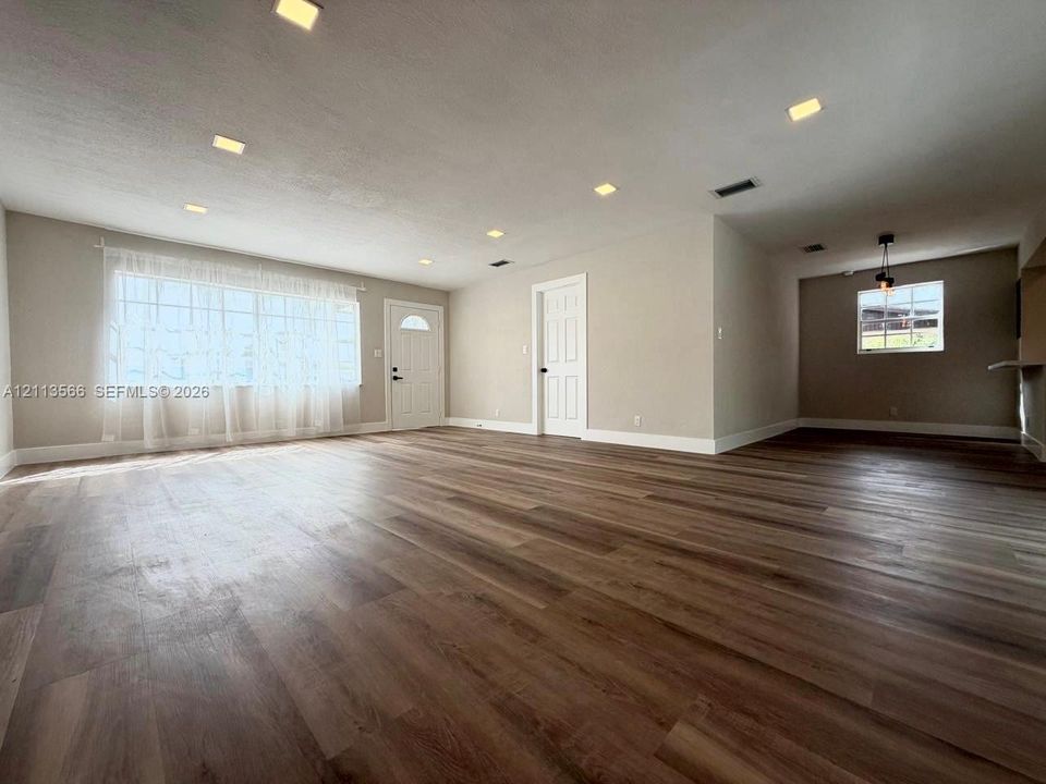 Open-concept interior featuring wood-finish flooring, recessed lighting, neutral wall tones, and multiple grid-pattern windows