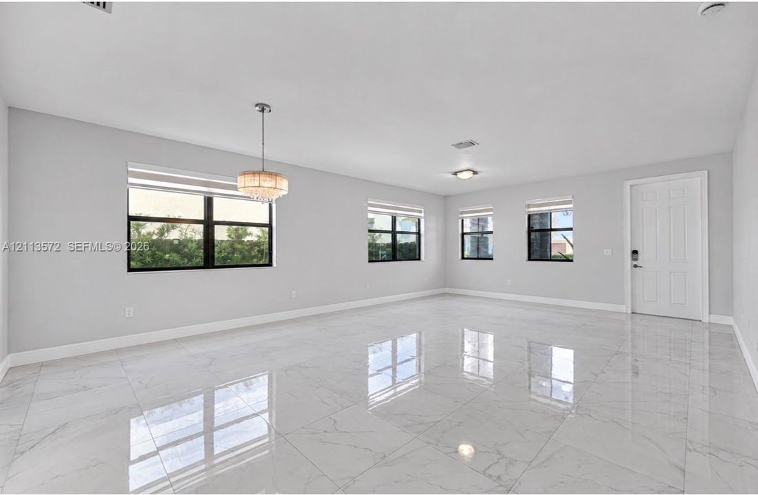 Polished stone-finish flooring, multi-pane windows with black frames, and a tiered crystal chandelier