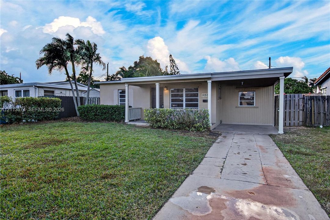 Single-story residence featuring a covered front porch, attached carport, concrete driveway, and established landscaping