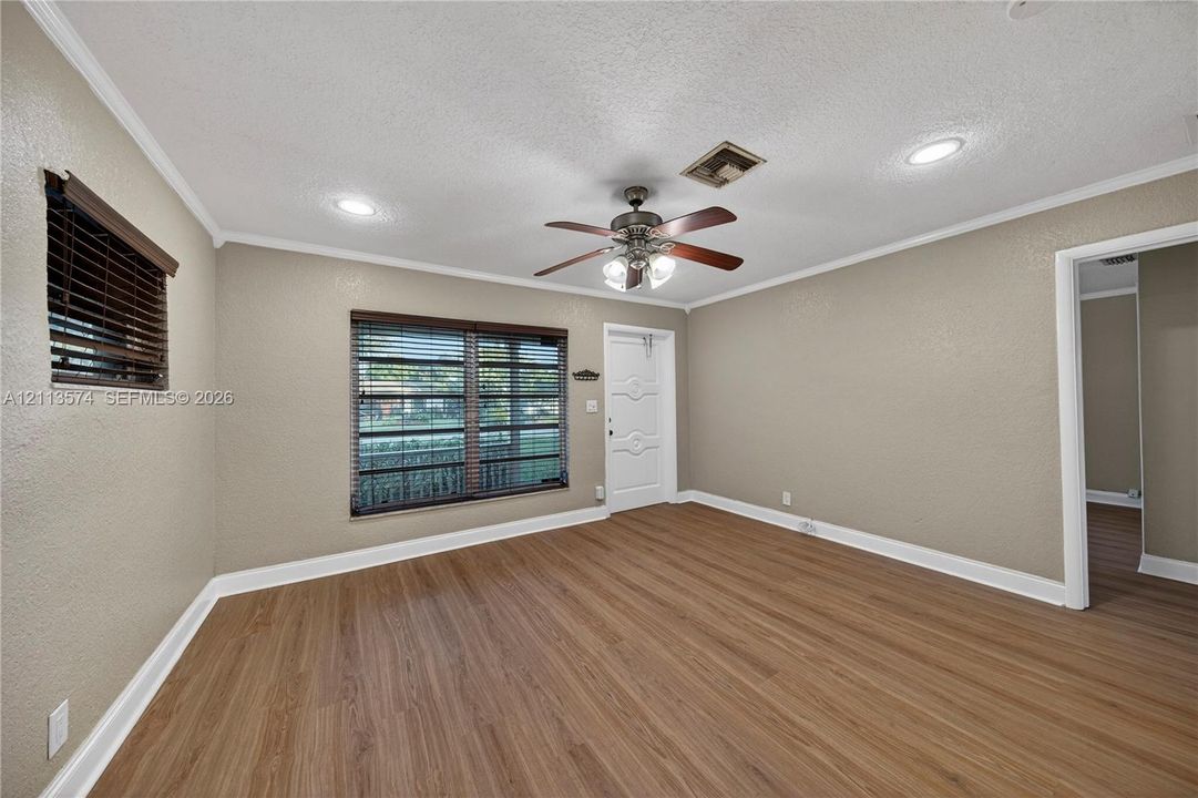 Interior space featuring wood-finish flooring, recessed lighting, a multi-blade ceiling fan with integrated light fixture, and windows equipped with horizontal blinds