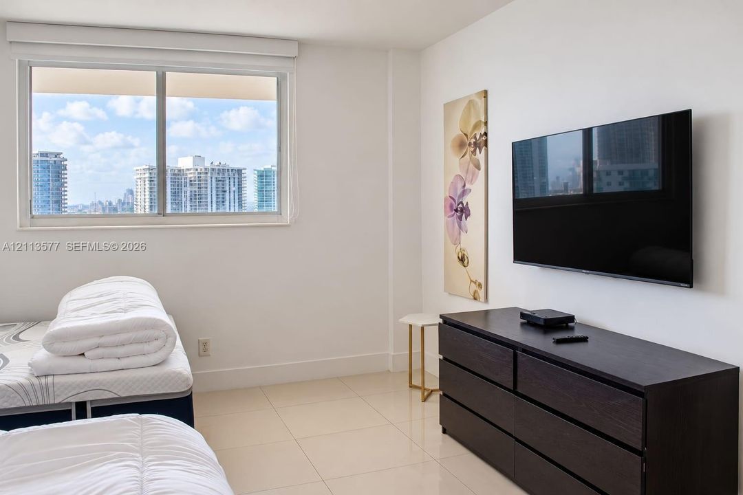 Large-format tile flooring, expansive window with city skyline, and neutral wall finishes