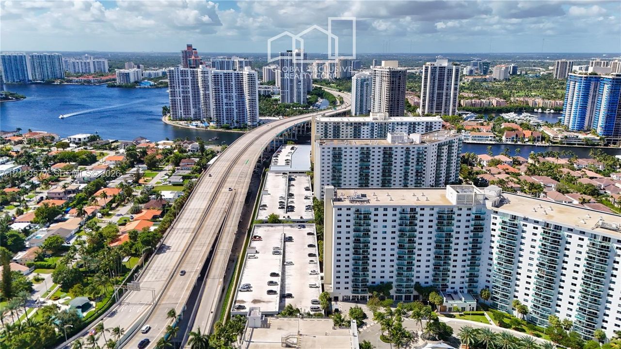 Aerial perspective featuring multi-story residential towers, coastal waterways, and proximity to infrastructure