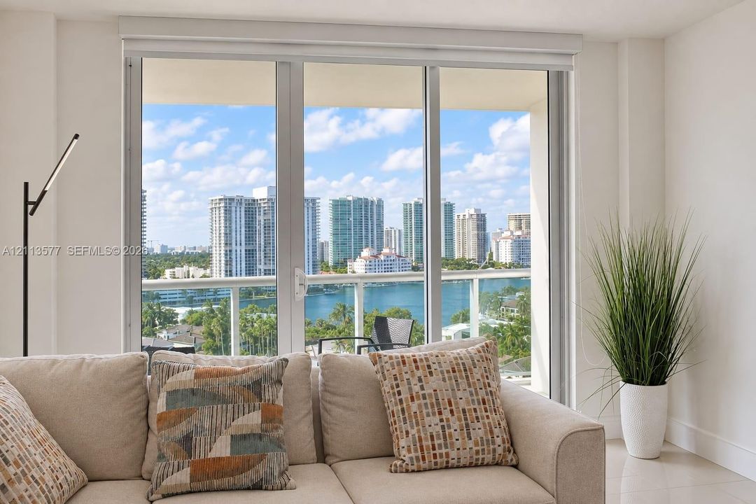 Floor-to-ceiling glass panel windows, glass-railing balcony, and expansive urban waterfront skyline scenery
