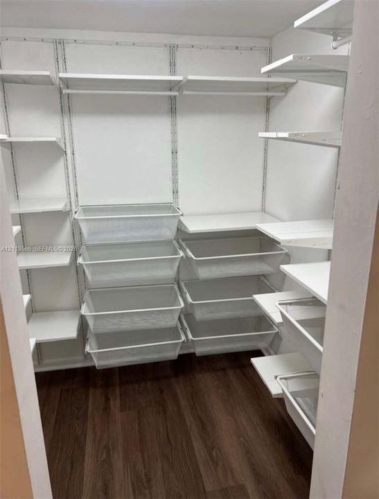 Customizable closet system featuring adjustable shelving, integrated wire-mesh drawers, and wood-finish flooring