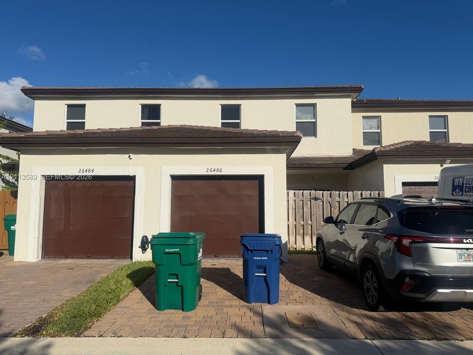 Stucco exterior featuring two-story construction, a tile roof, paved driveway, and dual attached garages