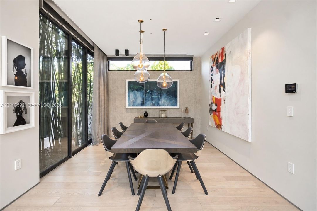 Dining area featuring wood-finish flooring, floor-to-ceiling sliding glass doors, horizontal clerestory windows, recessed ceiling lighting, and suspended glass globe pendant fixtures