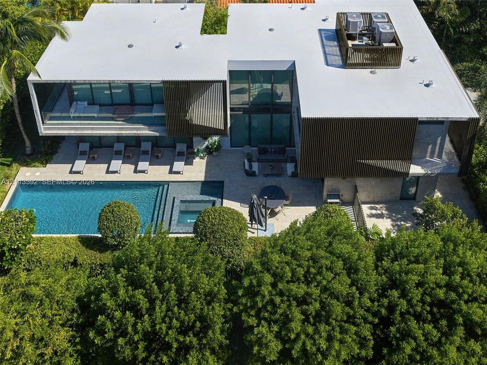 Contemporary architectural exterior featuring vertical wooden slatted screening, floor-to-ceiling glass windows, a rectangular swimming pool, and an integrated spa