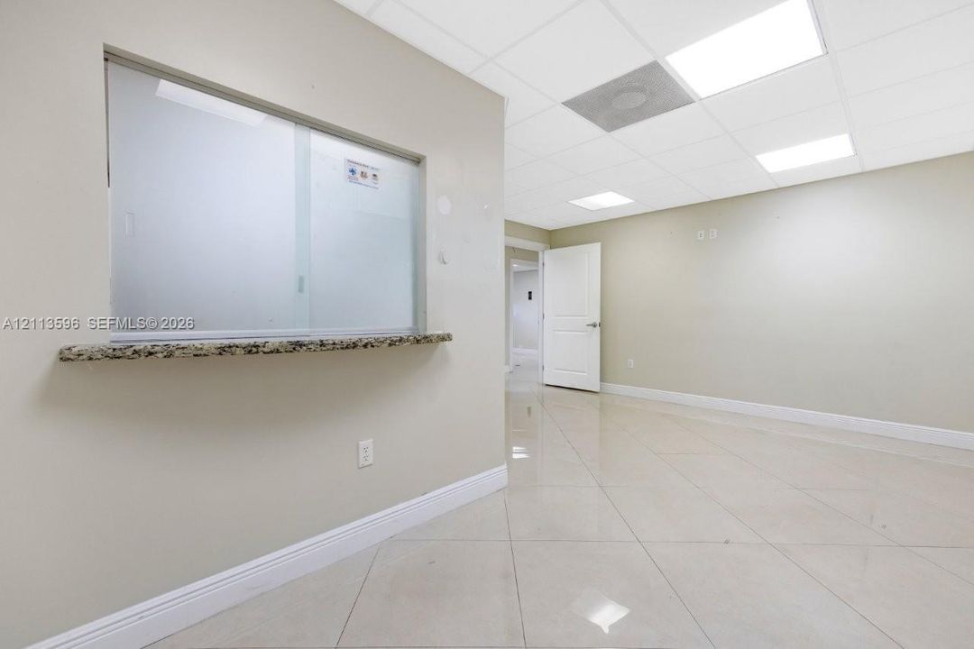 Interior space featuring polished tile flooring, drop ceiling with recessed lighting, a stone-finished service ledge, and a multi-panel door