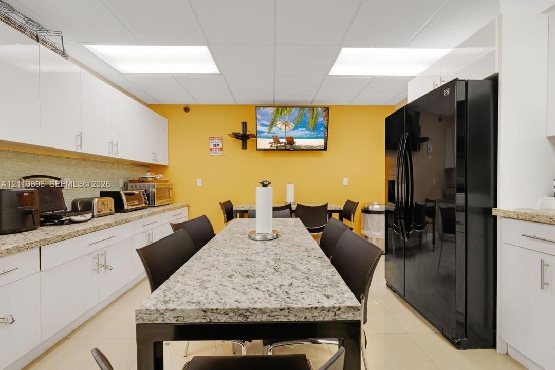 Kitchen featuring white cabinetry, stone-finish countertops, tile flooring, and integrated black double-door refrigerator